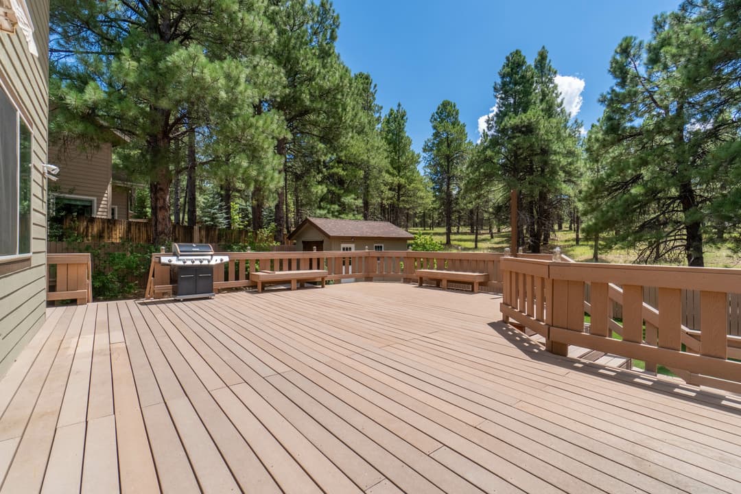 Spacious wooden deck surrounded by pine trees, ideal for outdoor relaxation and entertaining.
