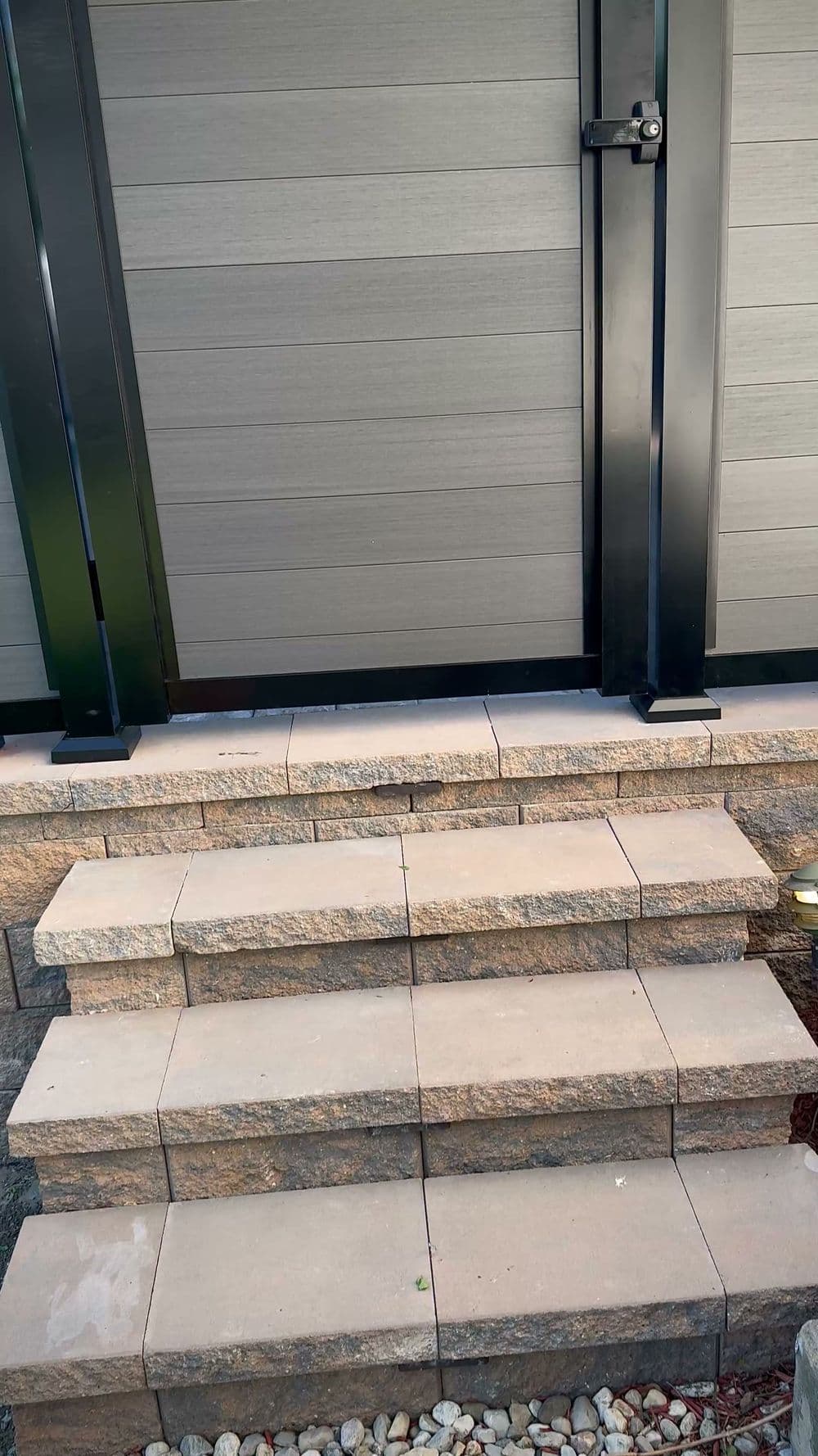 Stone steps leading to a fenced entrance, featuring modern design and subtle lighting.