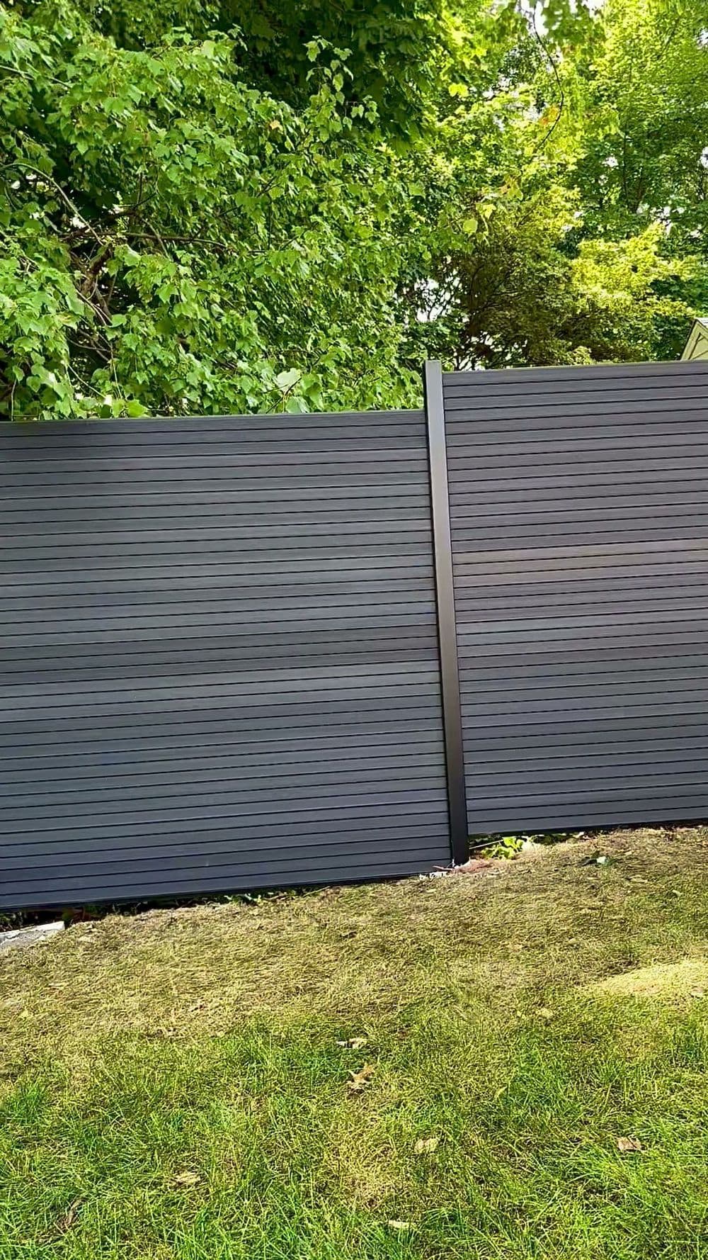 Modern black horizontal fence panels in a lush green garden setting.
