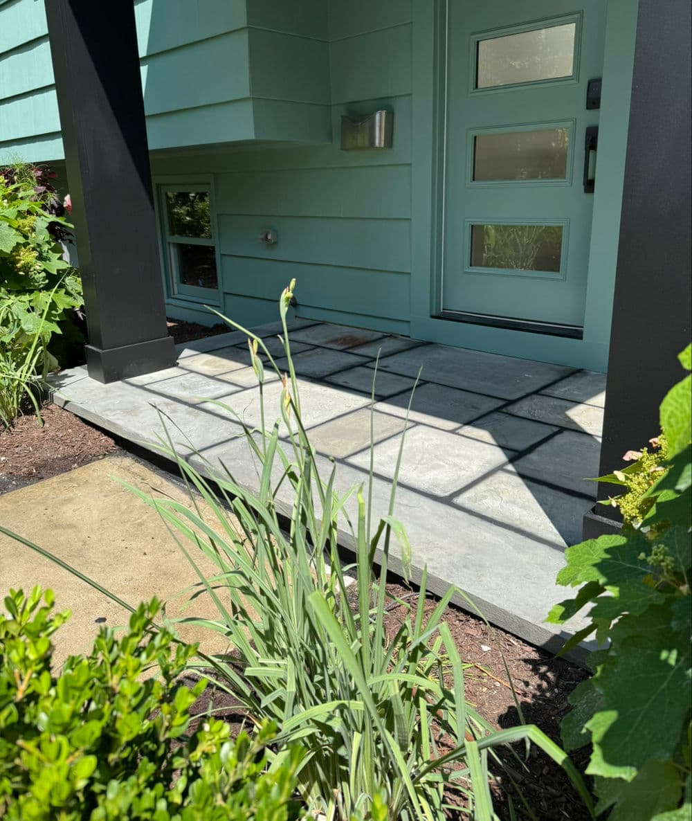 Front entrance featuring modern mint green door and stone pathway with lush greenery.